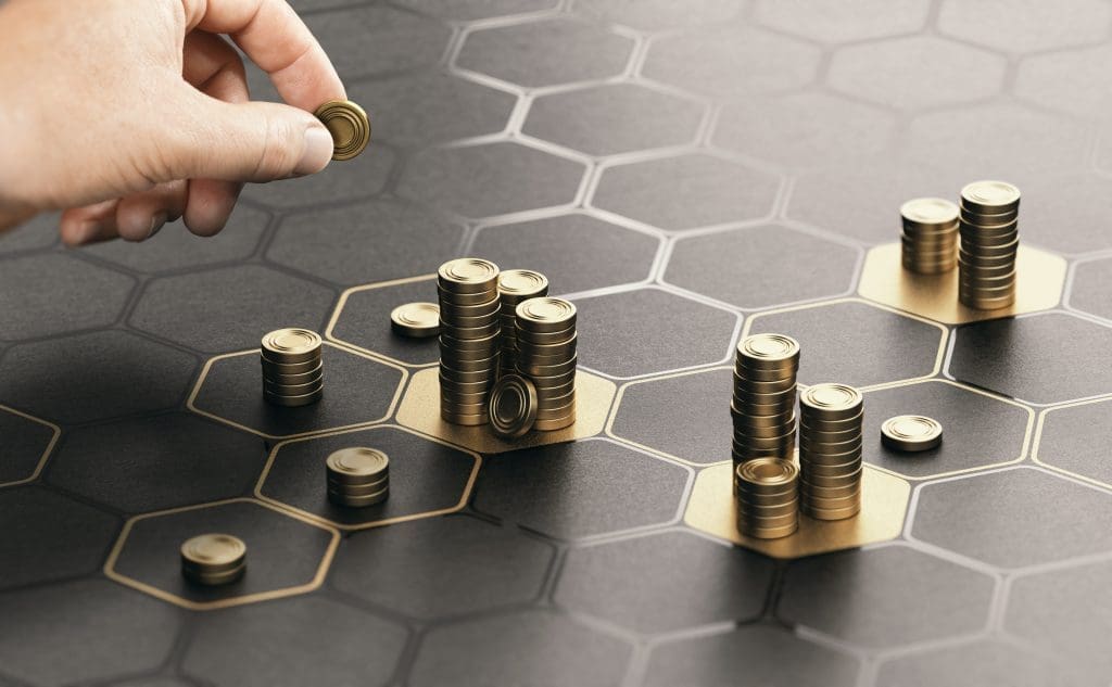 Human hand stacking gold coins on a black surface with a hexagonal pattern
