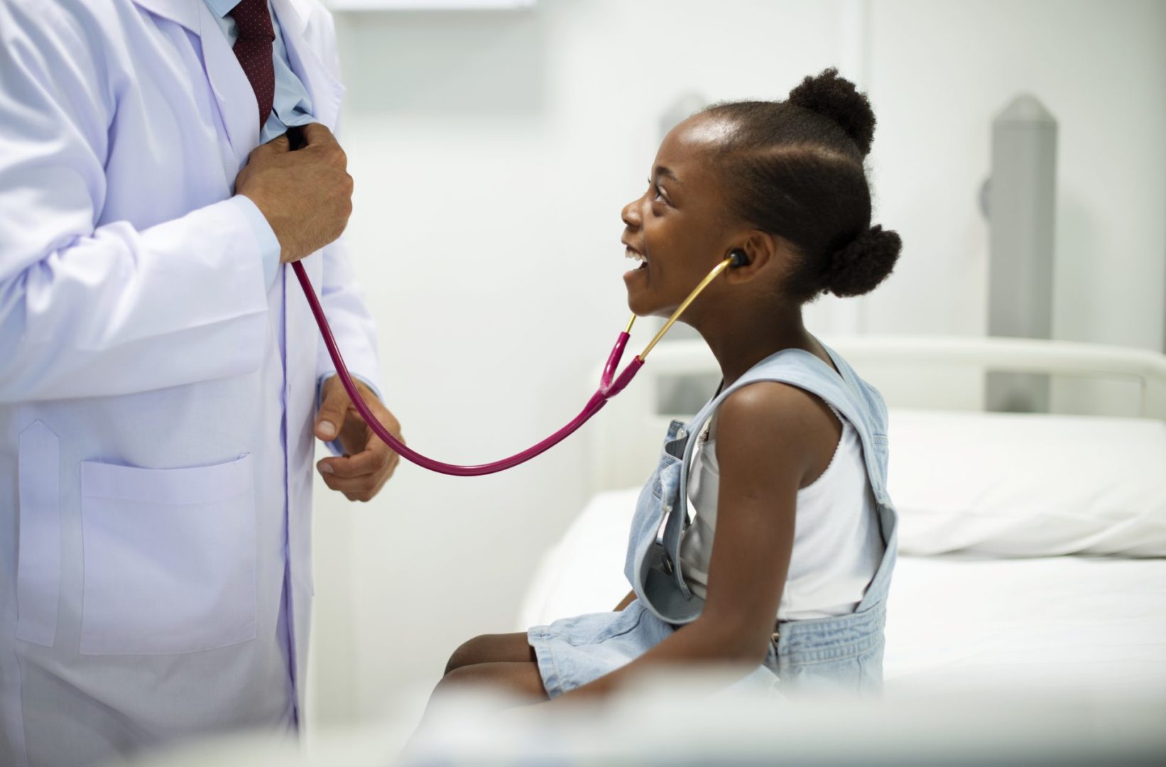 Friendly pediatrician entertaining his patient with his stethoscope