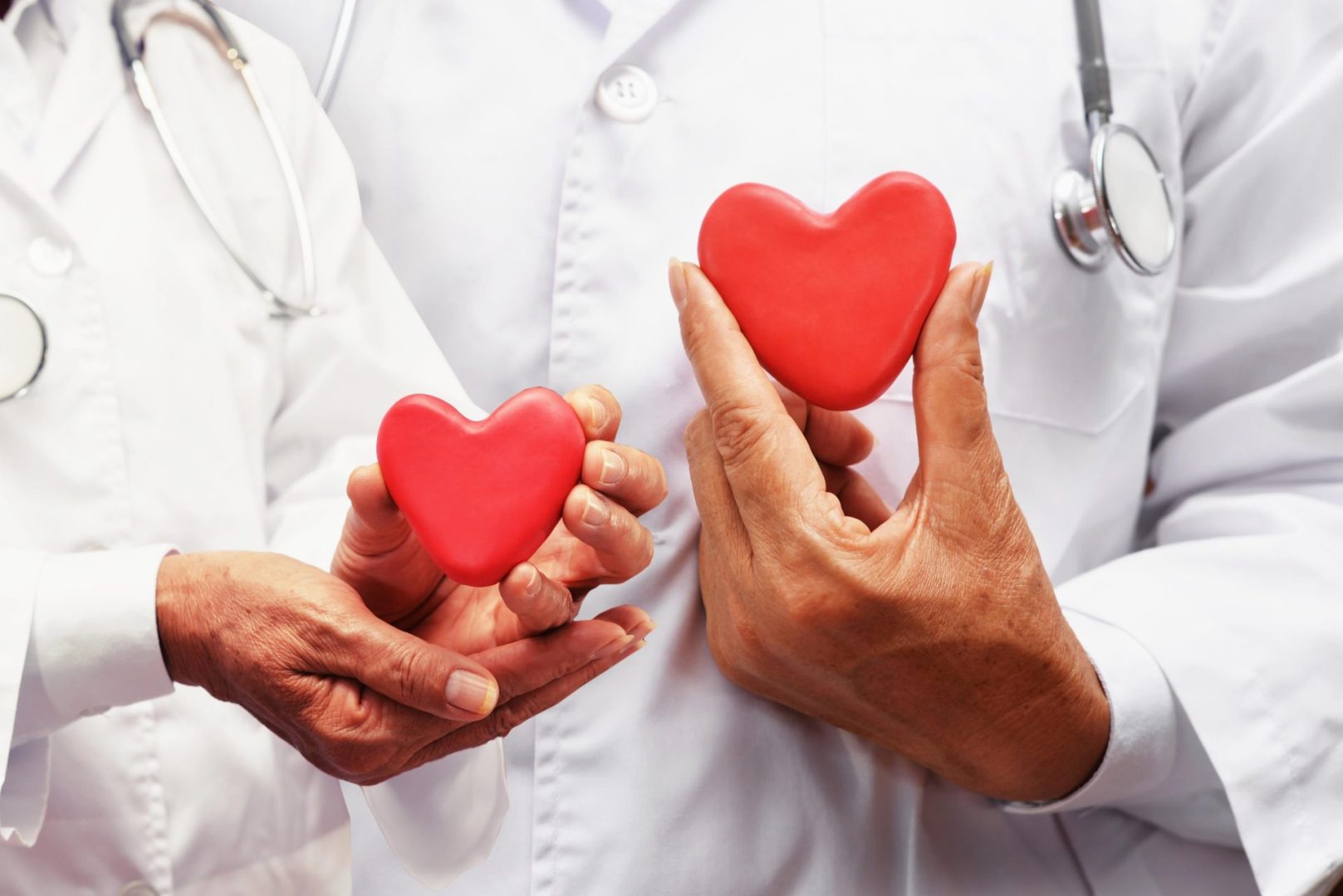two doctors holding red heart shaped objects in their hands
