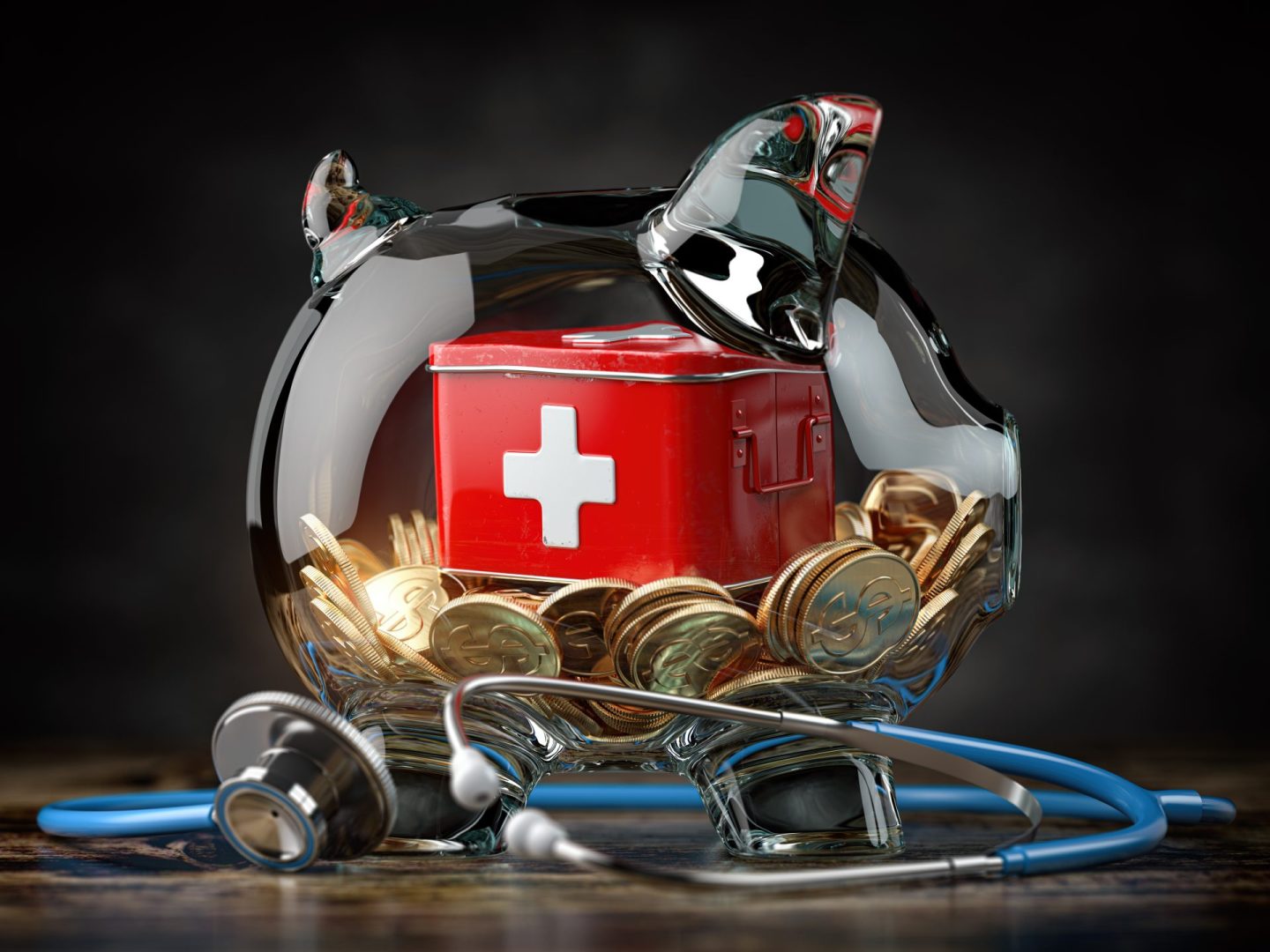 Glass piggy bank storing gold coins and a red tin box with a white cross healthy symbol on it. Doctor's stethoscope wraps around the piggy bank and rests on a wooden table against a black background