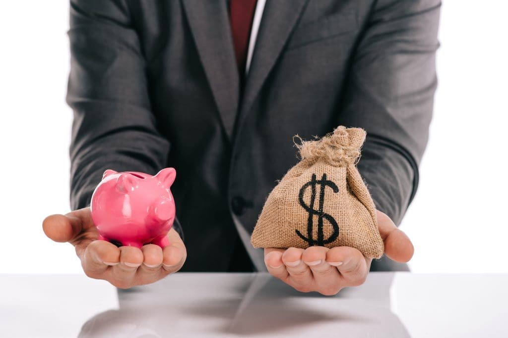cropped view of mortgage broker holding piggy bank and moneybag isolated on white