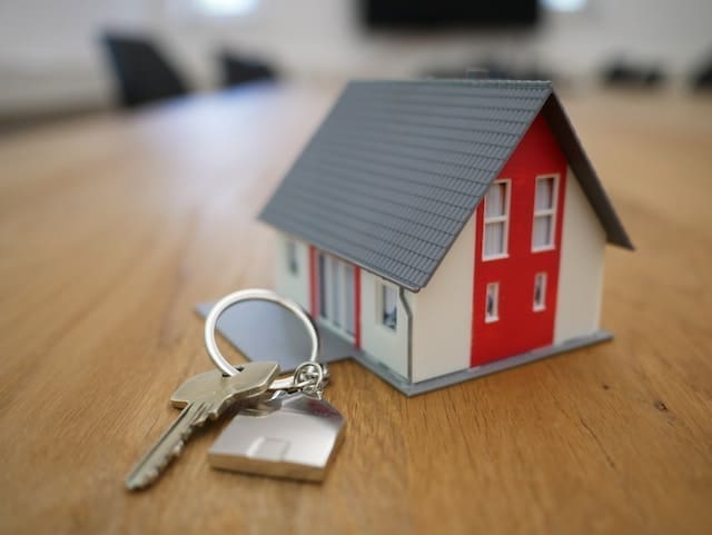 a small toy house with a set of keys in front on a wooden table
