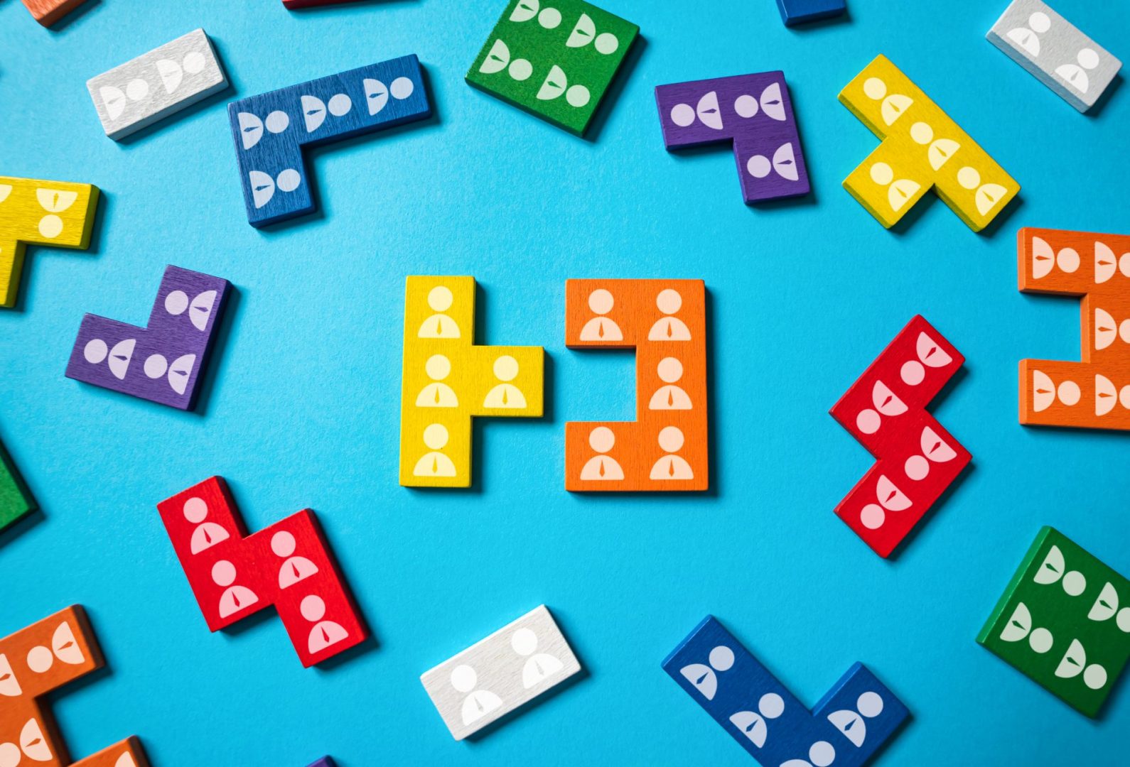 Colourful puzzle pieces decorated with personnel icons scattered across a blue surface.