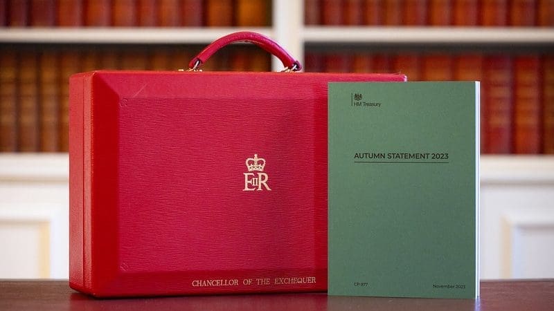 Red briefcase, decorated with Chancellor of the Exchequer Jeremy Hunt's name, next to green book promoting the 2023 Autumn Statement