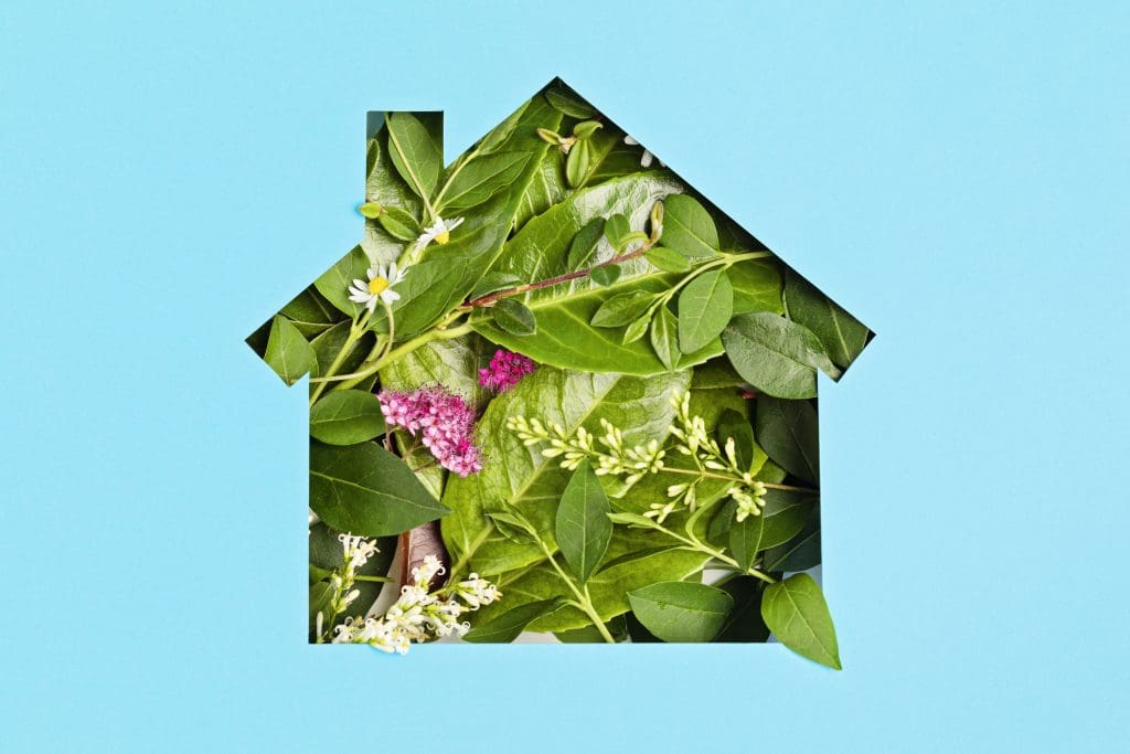 Paper cut house with green leaves and flowers.