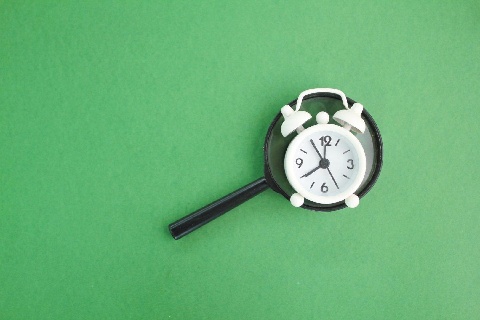 magnifying glass and bell clock on a green background