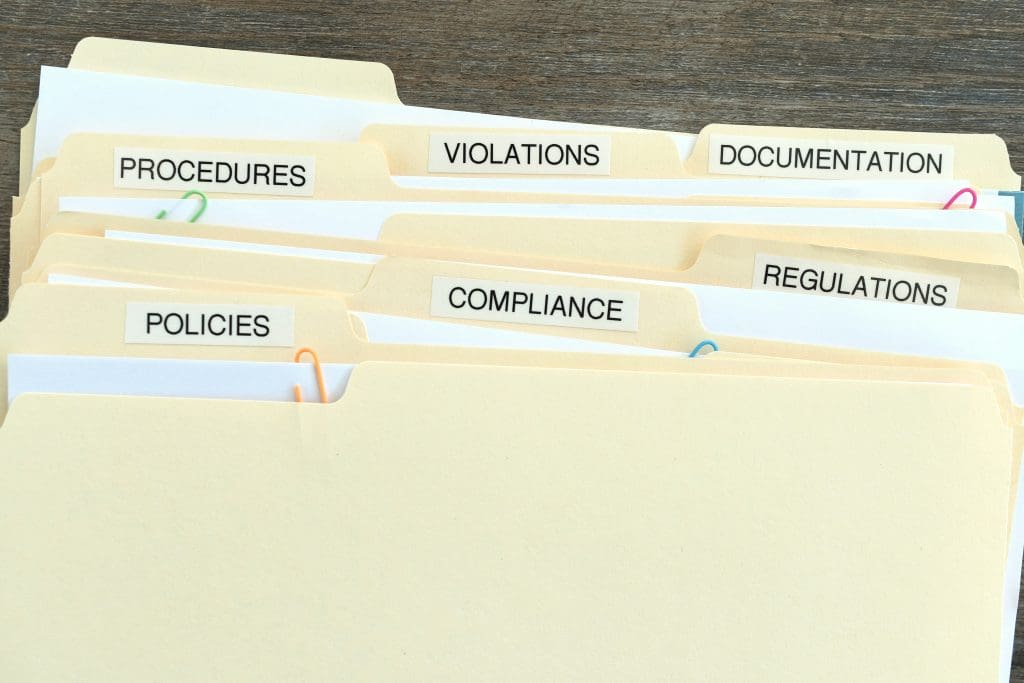 Compliance in the workplace. Folders containing paperwork regarding changing procedures to adhere to regulations policy procedure. As well as documenting violations.